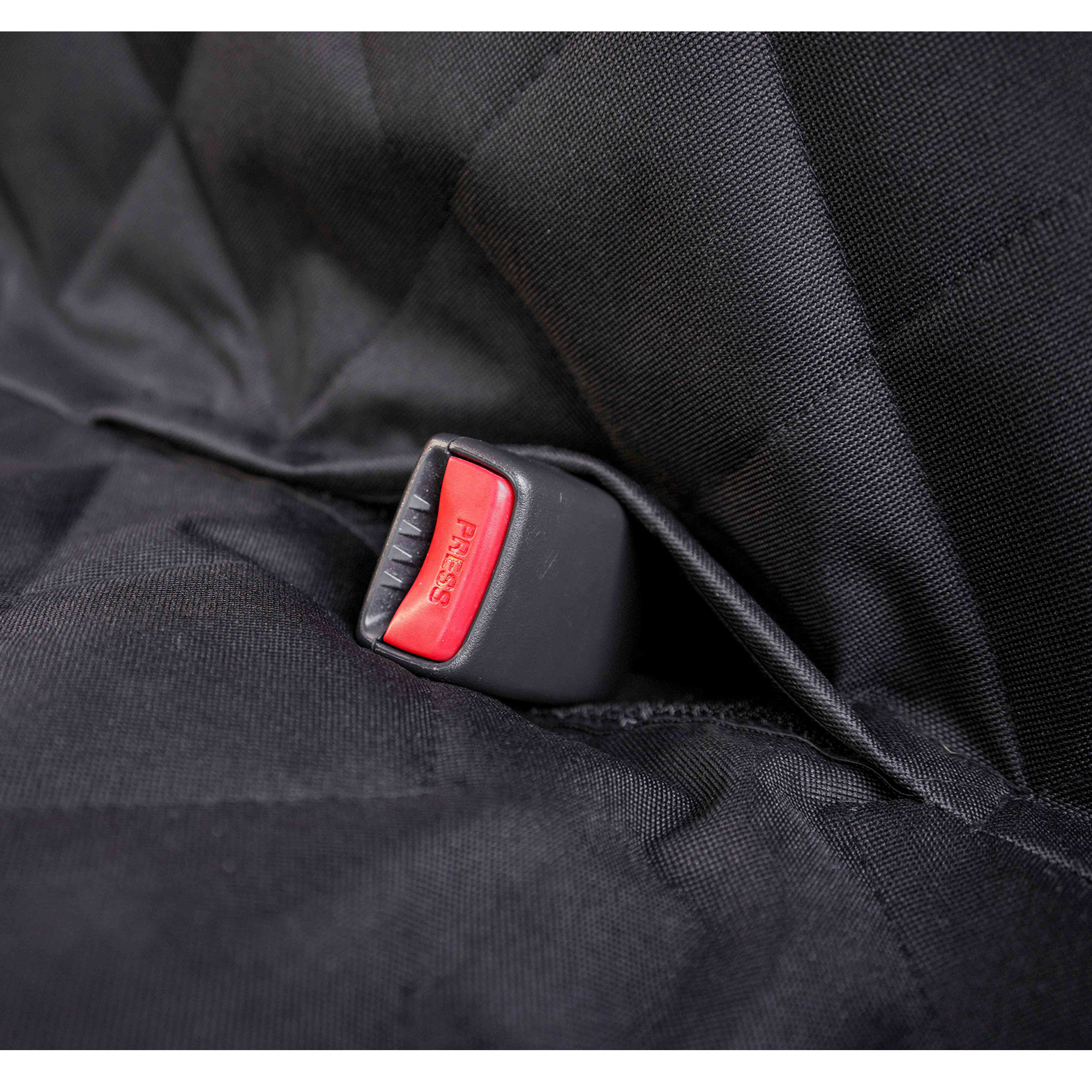 Close-up of seatbelt buckle slot opening through black pet car seat cover